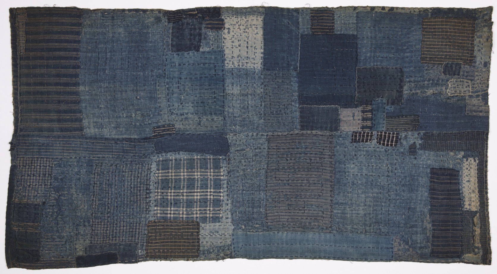 A late nineteenth-century Japanese boro sleeping mat: dozens of indigo cotton patches of different weaves held together with rows of sashiko running stitch, edges frayed and mended. Cooper Hewitt, Smithsonian Design Museum, 2017-15-1, public domain.