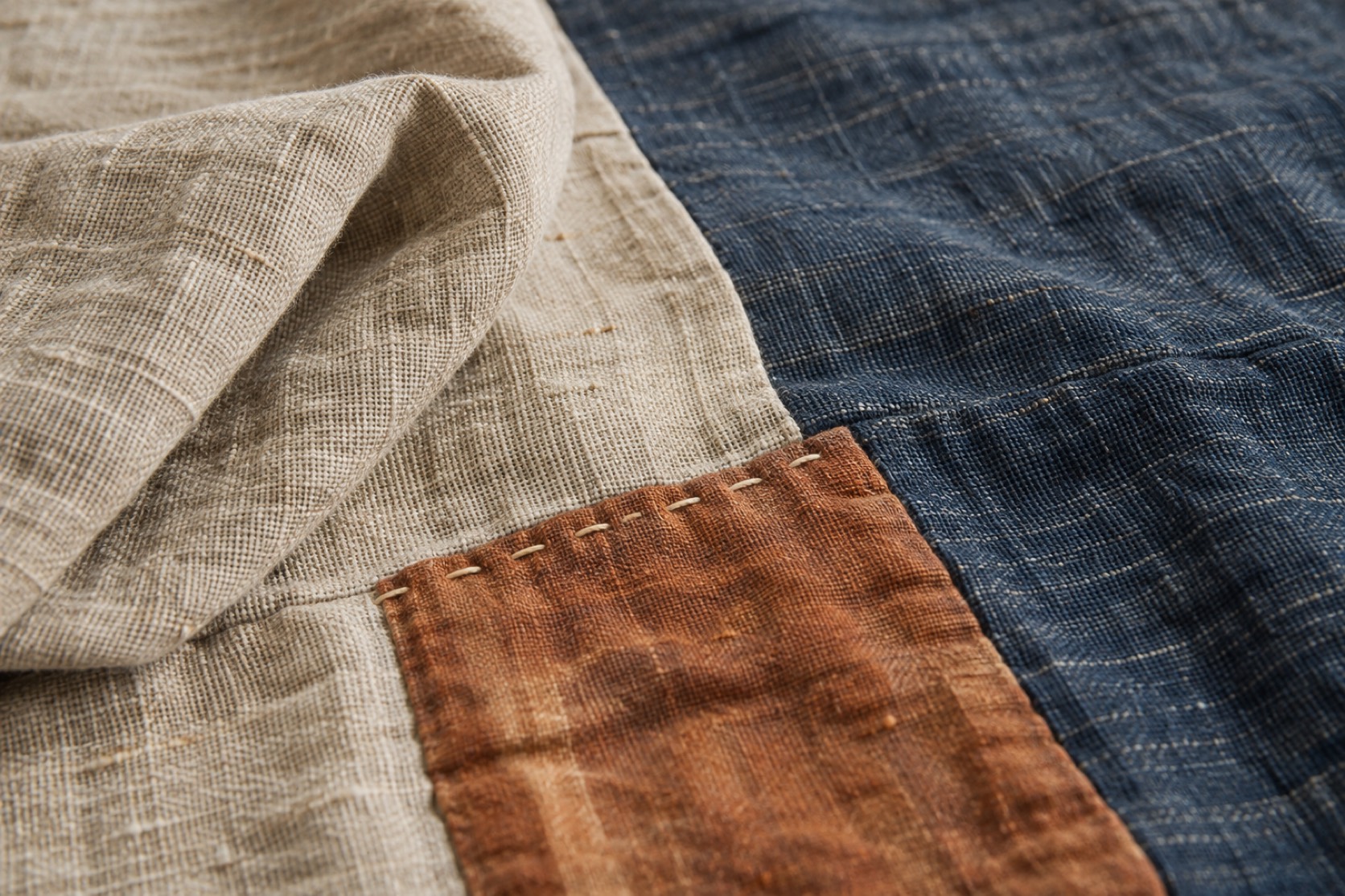 Macro view of irregular linen and indigo weave joined to a rust fabric patch.