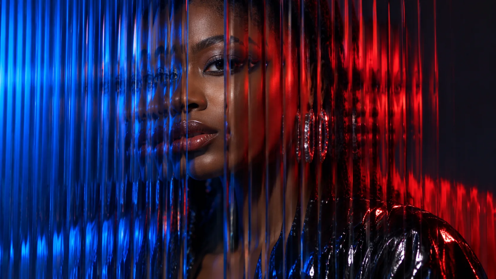 A blue-and-red fashion portrait smears and doubles through deeply ribbed glass.