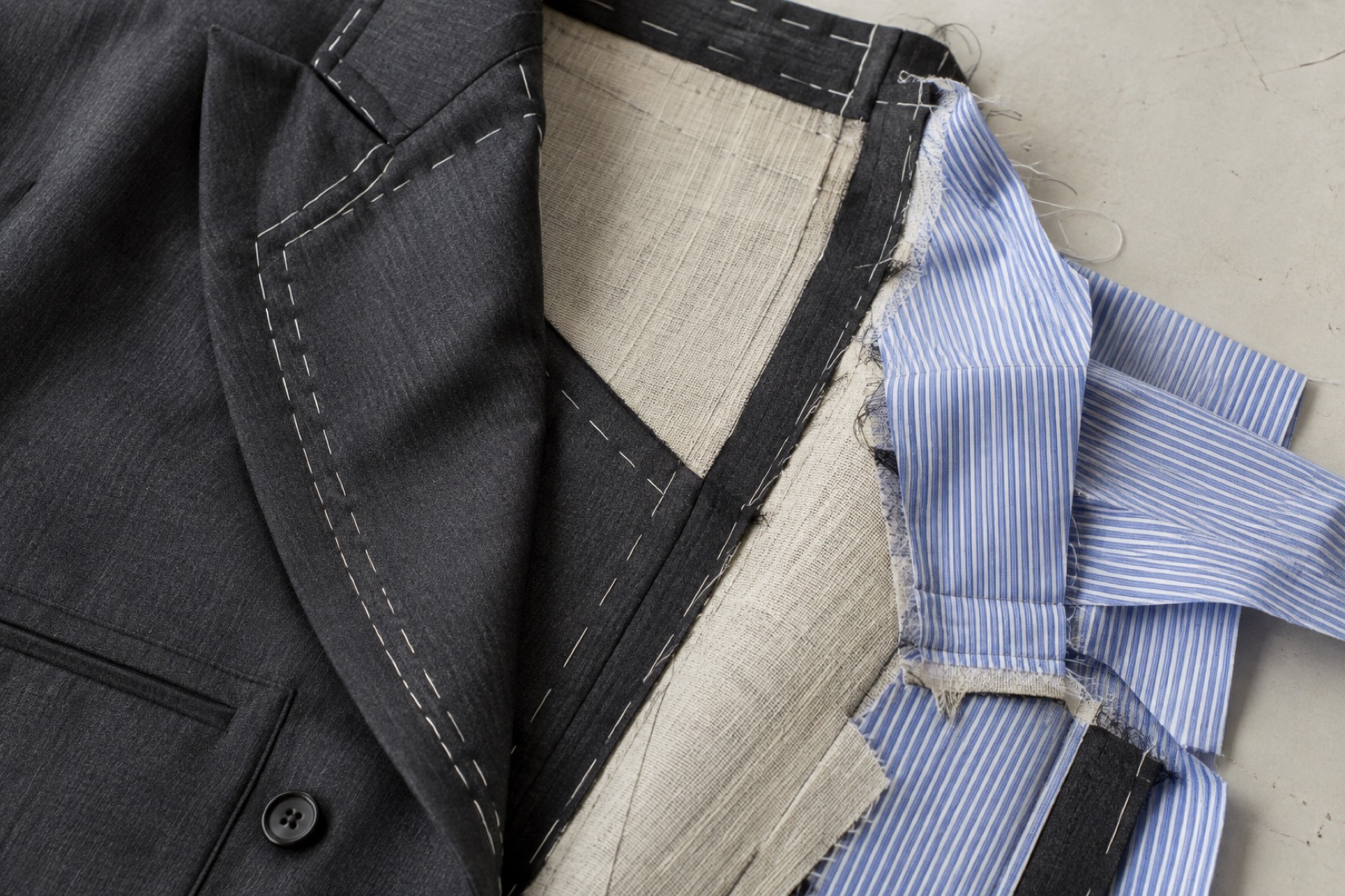 Charcoal wool, blue striped cotton and tailoring canvas show their seam allowances.