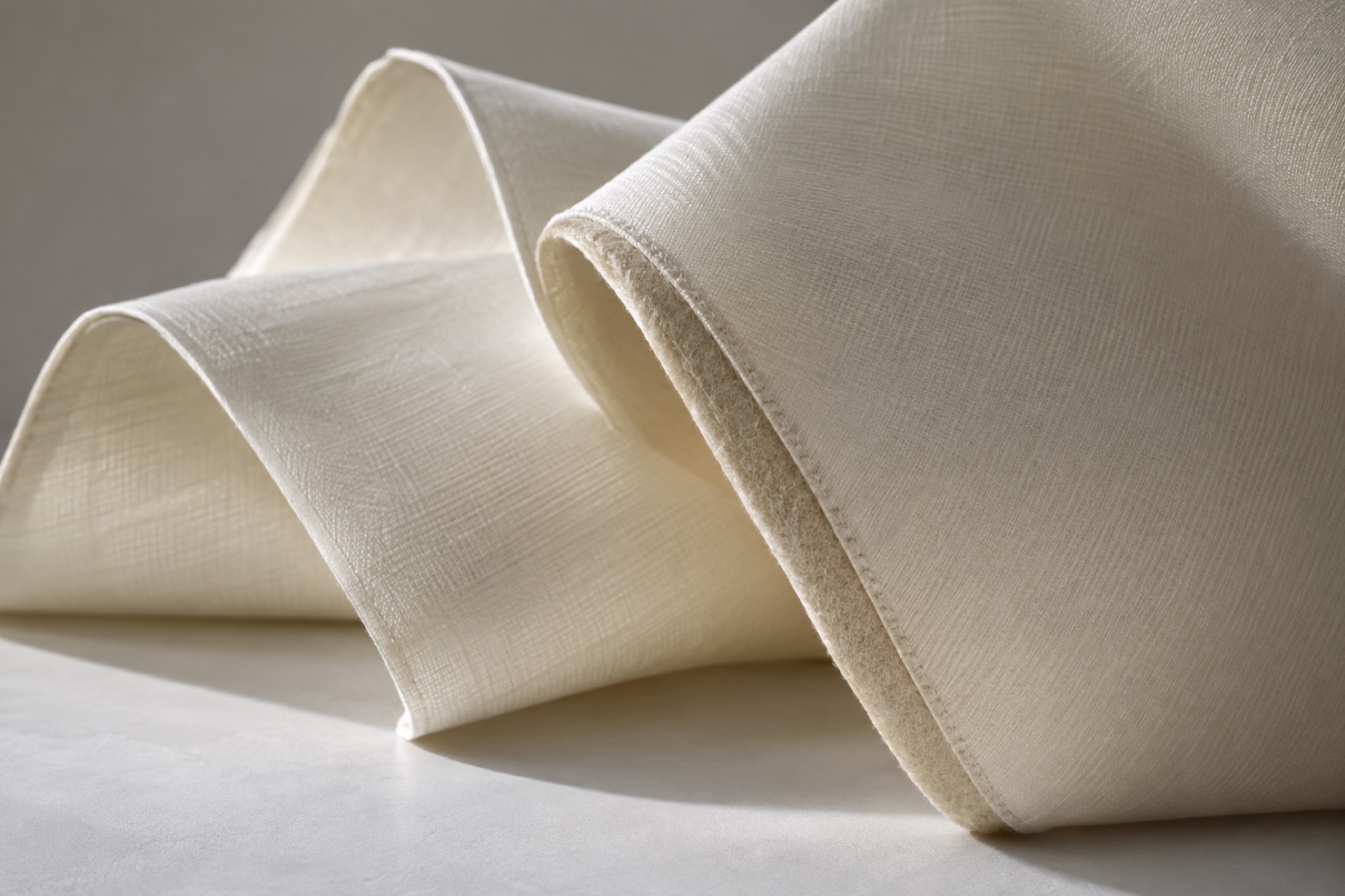 Ivory woven cloth forms crisp arcs with a visible stitched backing edge.